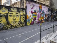 a colorful wall has been painted by various people on it's side, with two street railings