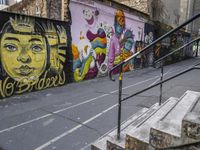 a colorful wall has been painted by various people on it's side, with two street railings