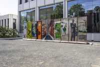 two colorful pieces of street art with building in background and trees reflected in glass window