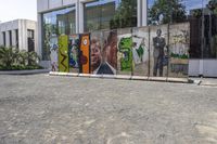 two colorful pieces of street art with building in background and trees reflected in glass window