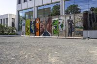 two colorful pieces of street art with building in background and trees reflected in glass window