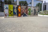 two colorful pieces of street art with building in background and trees reflected in glass window