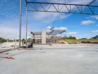 a large empty garage under a blue sky with clouds in the background and construction work is being done on a commercial building site