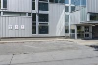 an empty street corner and a parking lot in front of a large building with lots of windows