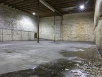 large empty concrete room with exposed ceiling and beams, showing fire hydrant outside, exposed wall behind