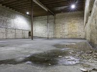 large empty concrete room with exposed ceiling and beams, showing fire hydrant outside, exposed wall behind