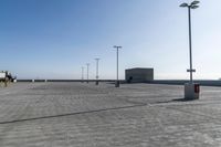 empty parking lot under a blue sky near lights and a beach area behind them or in the background