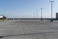 empty parking lot under a blue sky near lights and a beach area behind them or in the background