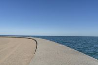 a beach covered in concrete with a sky background and water surrounding it with two blue sky