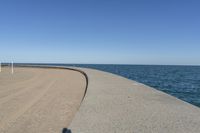 a beach covered in concrete with a sky background and water surrounding it with two blue sky