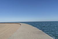 a beach covered in concrete with a sky background and water surrounding it with two blue sky