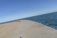 a beach covered in concrete with a sky background and water surrounding it with two blue sky