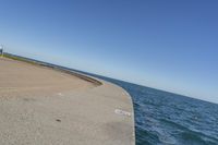 a beach covered in concrete with a sky background and water surrounding it with two blue sky