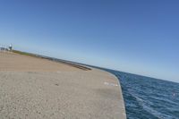 a beach covered in concrete with a sky background and water surrounding it with two blue sky