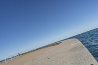 a beach covered in concrete with a sky background and water surrounding it with two blue sky