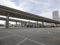 a highway overpass at an empty city parking lot below a bridge that connects two large streets