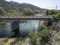 a view from a bridge overlooking trees and a mountain range of hills behind a bridge