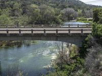 a view from a bridge overlooking trees and a mountain range of hills behind a bridge