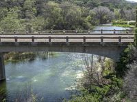 a view from a bridge overlooking trees and a mountain range of hills behind a bridge