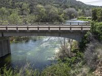 a view from a bridge overlooking trees and a mountain range of hills behind a bridge