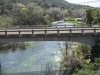 a view from a bridge overlooking trees and a mountain range of hills behind a bridge