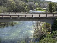 a view from a bridge overlooking trees and a mountain range of hills behind a bridge