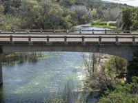 a view from a bridge overlooking trees and a mountain range of hills behind a bridge