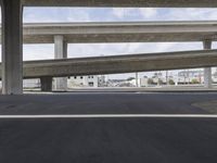 a black car parked on top of a empty road under two overpasses overpass