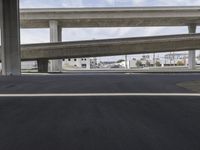 a black car parked on top of a empty road under two overpasses overpass