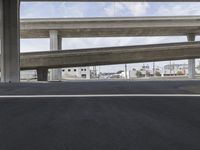 a black car parked on top of a empty road under two overpasses overpass