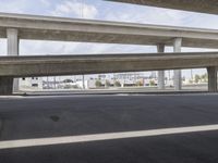 a black car parked on top of a empty road under two overpasses overpass