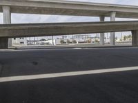 a black car parked on top of a empty road under two overpasses overpass