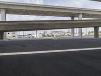 a black car parked on top of a empty road under two overpasses overpass