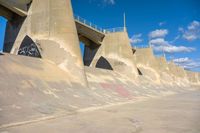 the concrete wall of a road that goes over a bridge and a man skateboarding