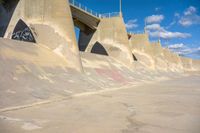 the concrete wall of a road that goes over a bridge and a man skateboarding