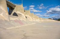 the concrete wall of a road that goes over a bridge and a man skateboarding