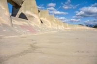 the concrete wall of a road that goes over a bridge and a man skateboarding