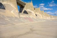 the concrete wall of a road that goes over a bridge and a man skateboarding