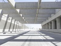 a concrete bridge over looking a city area, with large columns underneath the bridge and an open walkway on either side