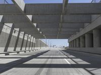 a concrete bridge over looking a city area, with large columns underneath the bridge and an open walkway on either side