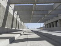 a concrete bridge over looking a city area, with large columns underneath the bridge and an open walkway on either side