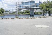 an empty parking lot next to a large bridge with people in the background and many bushes and bushes