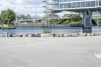 an empty parking lot next to a large bridge with people in the background and many bushes and bushes