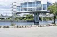 an empty parking lot next to a large bridge with people in the background and many bushes and bushes