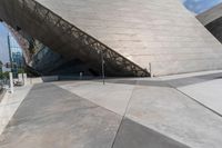 a man in white is outside a building and looks up at something, like a large, angled building