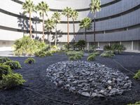 there is a circular garden made out of stones and plants in front of a building