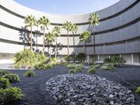 there is a circular garden made out of stones and plants in front of a building