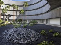 there is a circular garden made out of stones and plants in front of a building