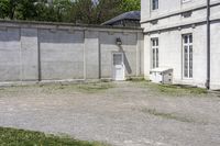 a cement building with a bench outside next to a brick wall and concrete wall in front of it