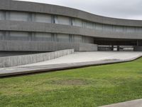 a building with cement roof near green grass and lawn in front of it, under a gray sky